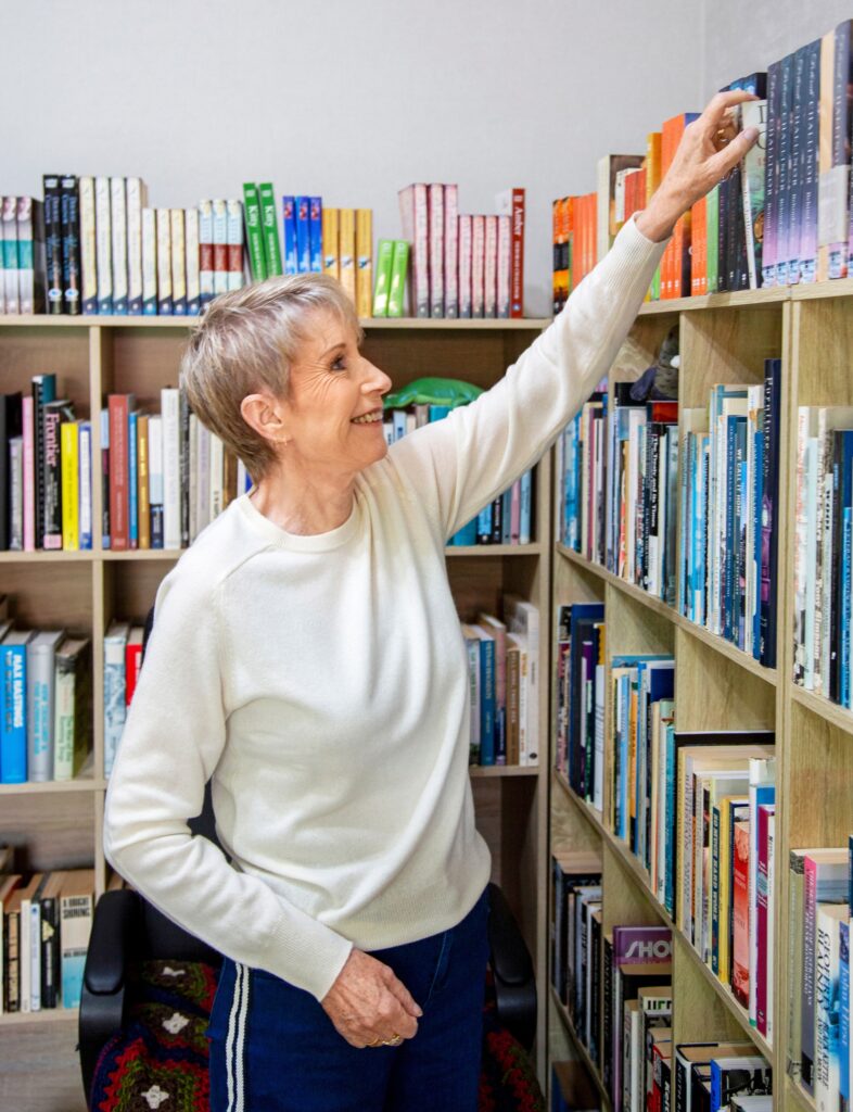 Deborah Challinor reaching for one of her history books at the top of a bookshelf