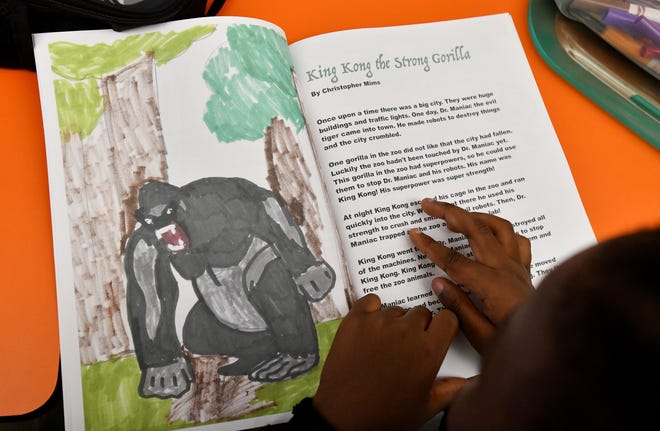 Young writer Christopher Mims reads over his book, "King Kong the Strong Gorilla at Wednesday's book signing party at the YMCA Tiger Academy on Jacksonville's northwest side, September 20, 2023. High School student Banks Vadeboncoeur and her group of volunteers run the Young Writers Workshop, a youth-led summer program dedicated to fostering a love of creative writing and reading among underserved children in Jacksonville. At the end of the workshop, each child wrote and published their own hardcover book.
