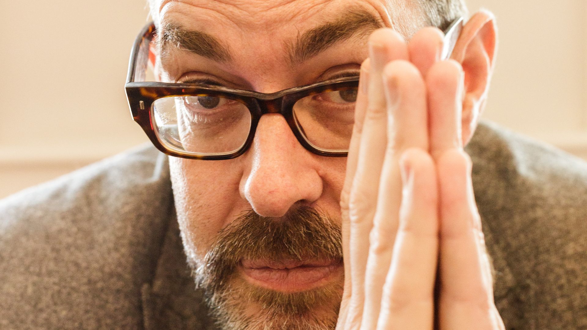 close-up photo of Richard Osman's face with his palms in a prayer position