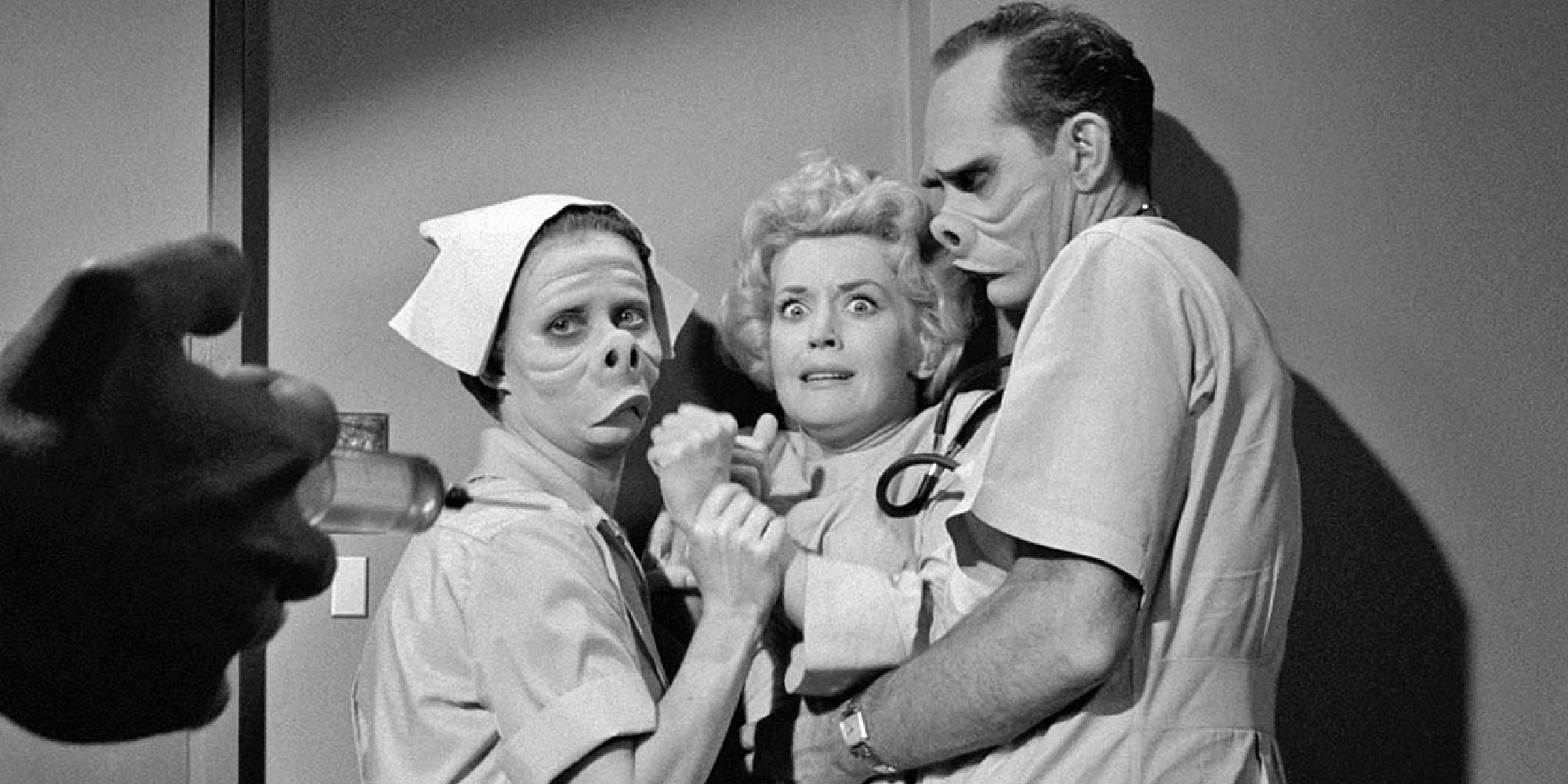 Jennifer Howard as Janet's Nurse and William Gordon as Dr. Bernardi with disfigured faces holding down Maxine Stuart as Janet Tylerwhile someone approaches with a syringe in Eye of the Beholder from The Twilight Zone