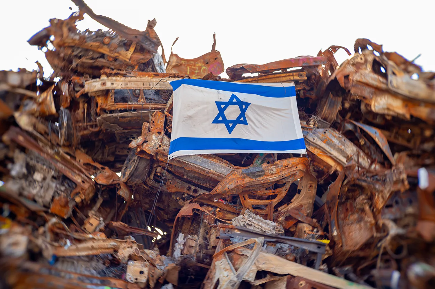 An Israeli flag sits amont a twisted pile of metal, the remains of damaged cars after the Hamas attacks on Israel.