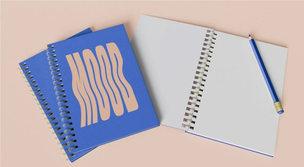 A blue notebook has the word “Mood” printed on its cover in decorative lettering.