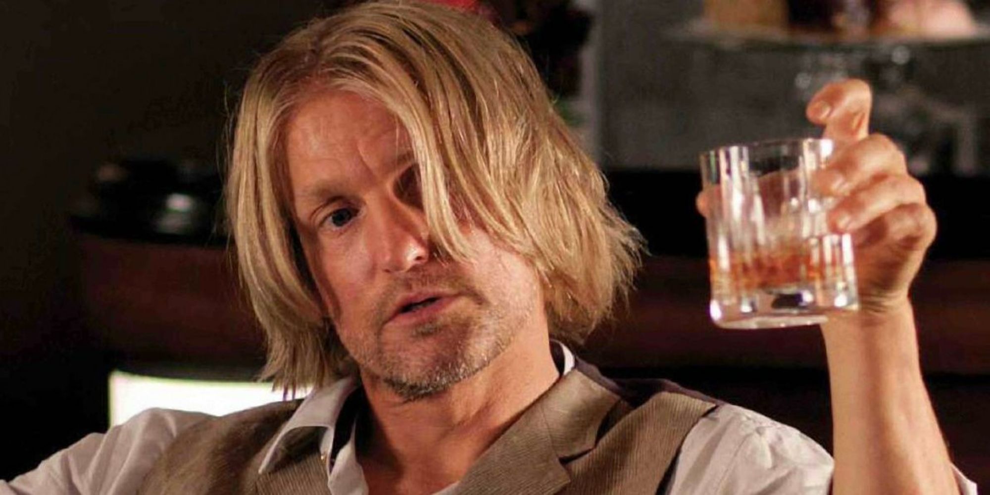 Woody Harrelson as Haymitch holding a glass of alcohol in The Hunger Games