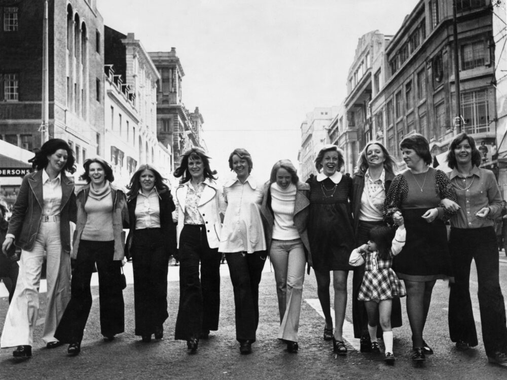 The wives and fiancees of Liverpool FC football players step out in style in Liverpool City Centre. They had just chosen their footwear at a Church Street store ahead of the 1974 FA Cup Final against Newcastle at Wembley. Left to right are: Geraldine Lawler, Barbara Hughes, Pat Saunderson (fiancé of Phil Thompson), Vera Clemence, Lynn Callaghan, Sue Smith, Marion Cormack, Jean Woodhouse (fiancé of Kevin Keegan), Mary Hall and Sue Lloyd. The little girl in front is Emma, daughter of Ian Callaghan. - Dirty Stop Out’s Guide to 1970s Liverpool