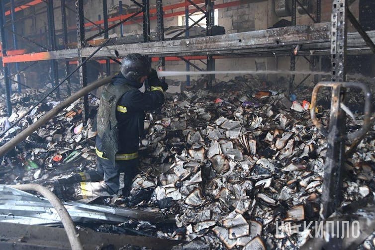 A fireman searches in the ashes of books at FaktorDruk printworks in Kharkiv
